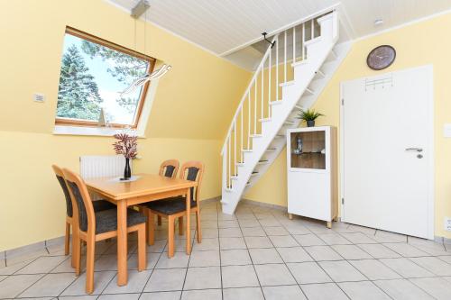 ein Esszimmer mit einem Tisch, Stühlen und einer Treppe in der Unterkunft Ferienhaus Daniela in Neuharlingersiel