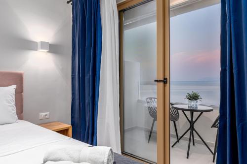a bedroom with a bed and a glass door with a table at Anasa Corfu in Benitses