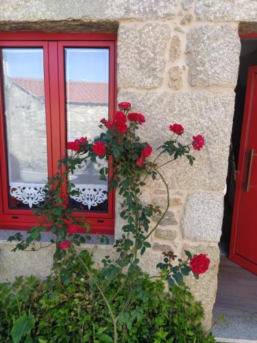 a window with red shutters and red flowers at A Casiña de Carmen in Boiro