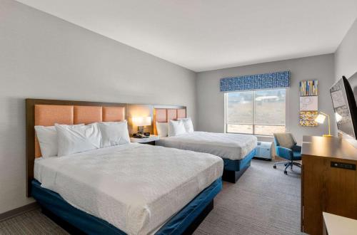 Hampton Inn Colorado Springs Northeast في كولورادو سبرينغز: غرفة فندقية بسريرين ونافذة