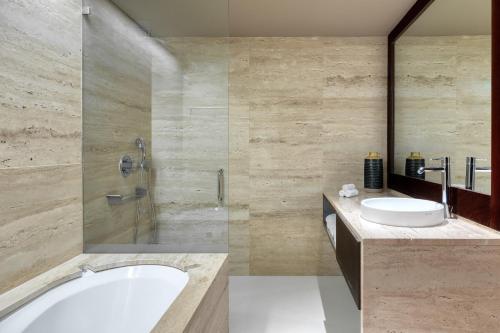 a bathroom with a tub and a sink and a shower at Domes Lake Algarve, Autograph Collection in Vilamoura