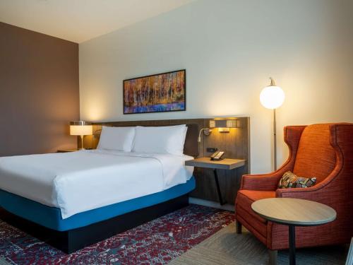um quarto de hotel com uma cama e uma cadeira em Hilton Garden Inn Jeffersonville, In em Jeffersonville