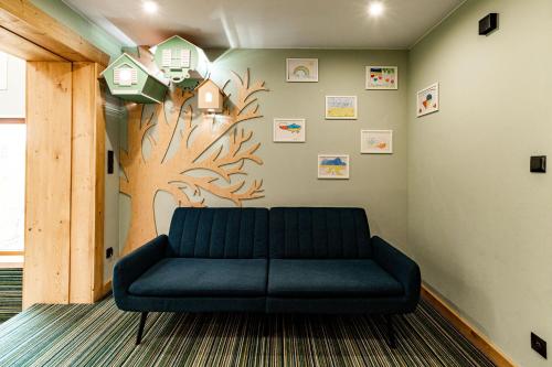 a couch in a room with a tree painted on the wall at Ku Dolinie in Kościelisko