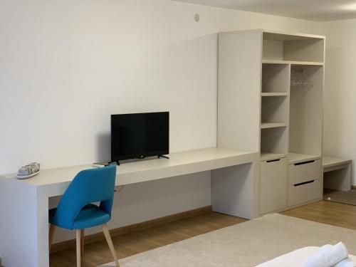 a desk with a tv and a blue chair at Royal L Hotel in Carev Dvor