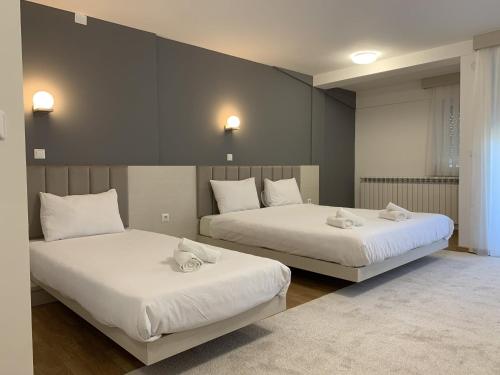 2 camas en una habitación con sábanas blancas en Royal L Hotel, en Carev Dvor