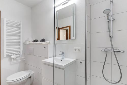 uma casa de banho branca com um chuveiro, um WC e um lavatório. em Apartment Schwarzwald em Schönwald