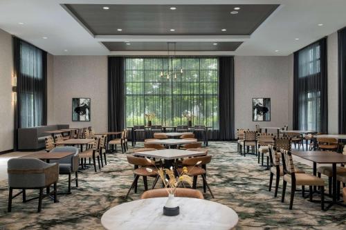 a dining room with tables and chairs and windows at Homewood Suites By Hilton Louisville Airport in Louisville
