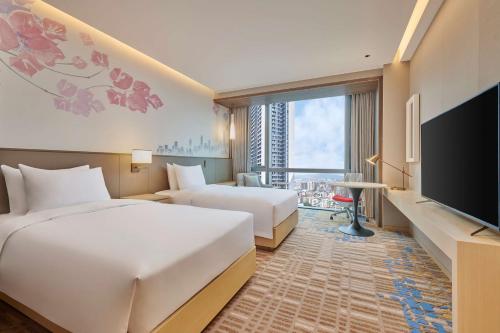 ein Hotelzimmer mit 2 Betten und einem Flachbild-TV in der Unterkunft Hilton Garden Inn Shenzhen Guangming in Shenzhen