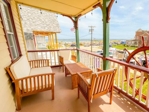 a porch with chairs and a wooden table on it at Beachliner Hotel in Ocean Grove