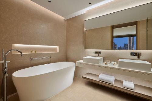 ein Badezimmer mit einer Badewanne, einem Waschbecken und einem Spiegel in der Unterkunft Hilton Garden Inn Shenzhen Guangming in Shenzhen
