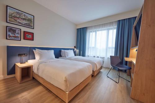 a hotel room with two beds and a desk at Hampton By Hilton Poznan Swarzedz in Swarzędz
