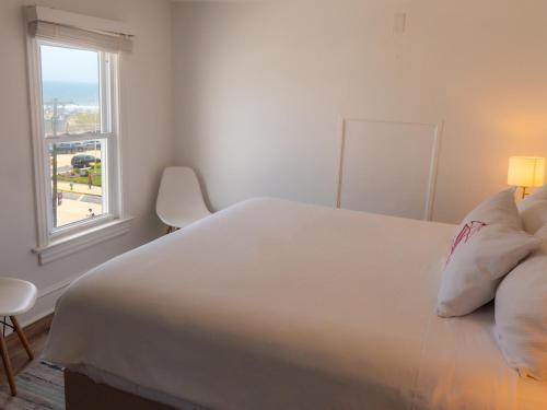 a bedroom with a large white bed and a window at Beachliner Hotel in Ocean Grove