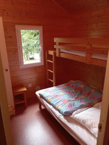 une chambre avec deux lits superposés et une fenêtre dans l'établissement Chalet les Hameaux du Perrier, à Lissac-sur-Couze