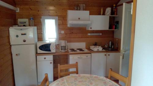 a small kitchen with white appliances and a table at Chalet les Hameaux du Perrier in Lissac-sur-Couze