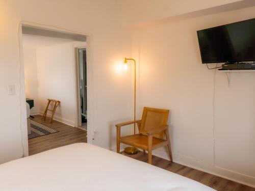 海洋林的住宿－Beachliner Hotel，一间卧室配有一张床和一把椅子,墙上配有电视。