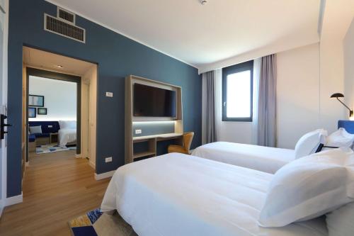 a hotel room with two beds and a television at Hampton by Hilton Rome North Fiano Romano in Fiano Romano