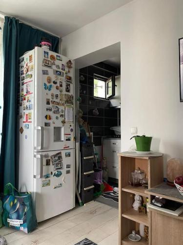 Il comprend une cuisine équipée d'un réfrigérateur blanc avec de nombreux aimants. dans l'établissement Apartament 3 camere confortabil, complet utilat, à Iaşi
