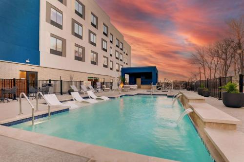 a large swimming pool with chairs and a building at Hampton Inn & Suites Weatherford, Tx in Weatherford