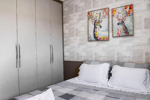 a bedroom with a bed with two paintings on the wall at Acomodação Extraordinária em sua viagem - LoftFelau in Cuiabá