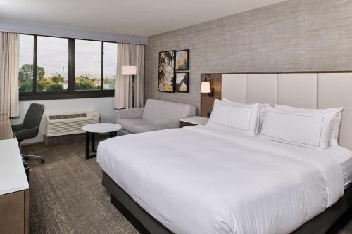 um quarto de hotel com uma cama grande e uma cadeira em Doubletree by Hilton Buena Park em Buena Park