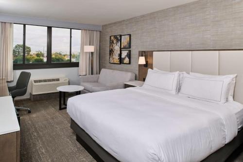 博伟公园Doubletree by Hilton Buena Park的配有一张大床和一把椅子的酒店房间