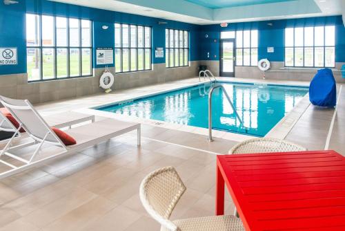 a swimming pool with a red bench and chairs in a building at Hilton Garden Inn Mattoon, IL in Mattoon