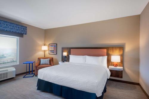 a hotel room with a large bed and a chair at Hampton Inn Kansas City Southeast, Mo in Kansas City