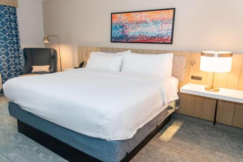 a large white bed in a hotel room with a chair at Hilton Garden Inn Mattoon, IL in Mattoon