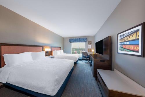 a hotel room with two beds and a flat screen tv at Hampton Inn Kansas City Southeast, Mo in Kansas City
