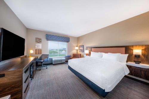 a hotel room with a bed and a flat screen tv at Hampton Inn Kansas City Southeast, Mo in Kansas City