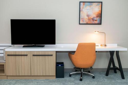 a desk with a television and a chair in a room at Hilton Garden Inn Mattoon, IL in Mattoon
