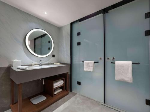 a bathroom with a sink and a shower with a mirror at Hilton Garden Inn Lhasa in Lhasa