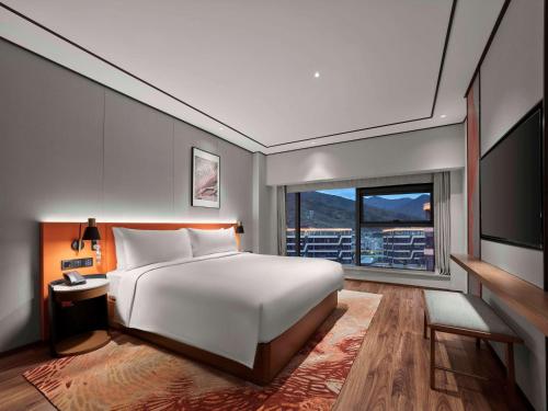 Hilton Garden Inn Lhasa في لاسا: غرفة نوم بسرير ابيض كبير ونافذة كبيرة