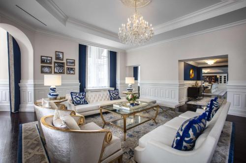 a living room with white furniture and a chandelier at Waldorf Astoria Washington DC in Washington