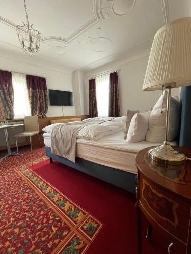 a bedroom with a bed and a table with a lamp at Hotel Garni Ratstube in Bad Urach