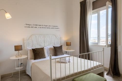 a bedroom with a white bed and a window at Casa dei Ré in Siracusa