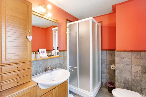 bagno con pareti arancioni, lavandino e doccia di Maison Grange 1 a Gressan