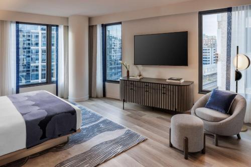 a bedroom with a bed and a tv and a chair at The Morrow Washington Dc, Curio Collection By Hilton in Washington