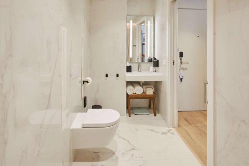 a white bathroom with a toilet and a sink at Via Sants Hotel Barcelona, Tapestry Collection By Hilton in Barcelona