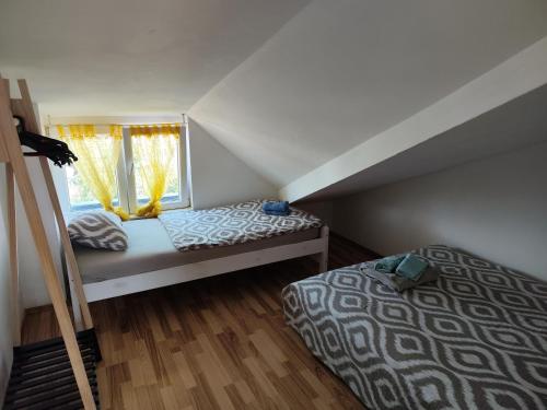 1 dormitorio en el ático con 2 camas y ventana en Apartments Ivo, en Njivice