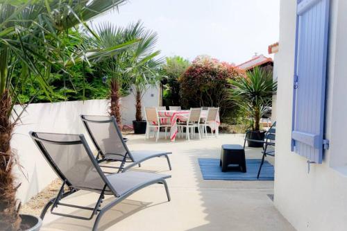 um pátio com cadeiras e uma mesa num quintal em Jolie Villa à 400m des plages de sable em La Plaine-sur-Mer