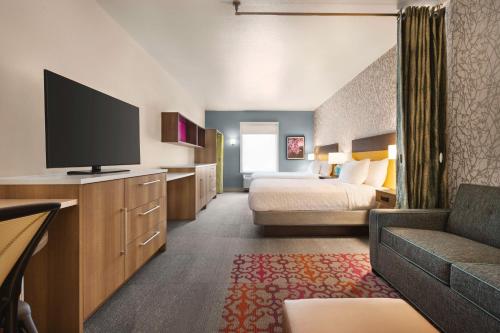a hotel room with a bed and a flat screen tv at Home2 Suites By Hilton Colorado Springs I-25 Central in Colorado Springs