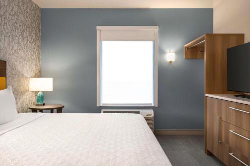 a bedroom with a bed and a window and a television at Home2 Suites By Hilton Colorado Springs I-25 Central in Colorado Springs