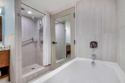 ein weißes Bad mit einer Badewanne und einer Dusche in der Unterkunft Hilton Vacation Club Flamingo Beach Sint Maarten in Simpson Bay