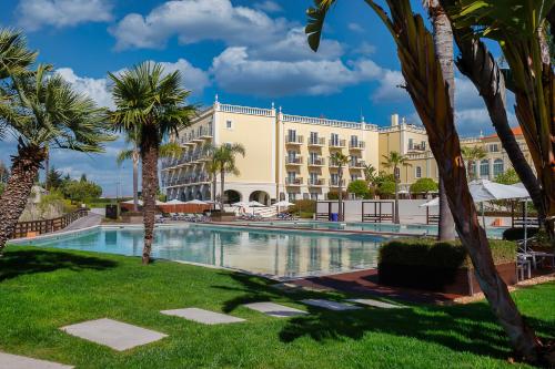 a swimming pool with palm trees in front of a building at Domes Lake Algarve, Autograph Collection in Vilamoura
