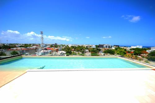 a large swimming pool with a view of a city at Spacious Studio, incredible rooftop with sea view in Playa del Carmen