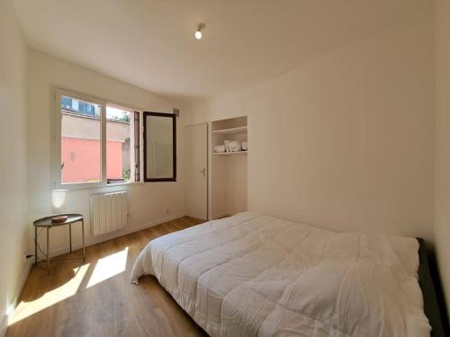 ein weißes Schlafzimmer mit einem großen Bett und einem Fenster in der Unterkunft Milan - Au milieu des Maisons de Champagne in Reims