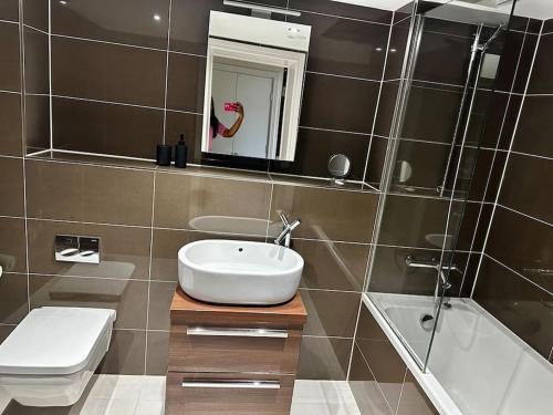 a bathroom with a sink and a toilet and a mirror at Modern 1bedflat Kensington in London