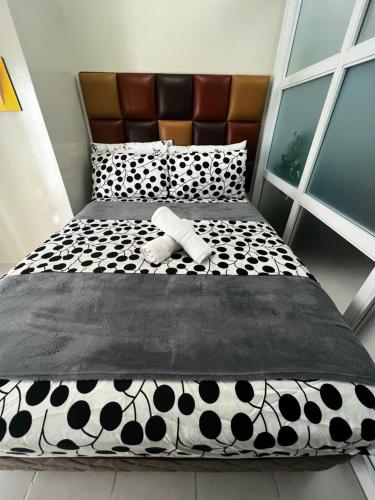 a bed with a black and white comforter and a pillow at Netflix and Unli WIFI!!! The Elchies Room at Tagaytay Prime Residence in Tagaytay