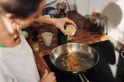 a woman is cooking food in a pan on a stove at pentahotel Eisenach in Eisenach